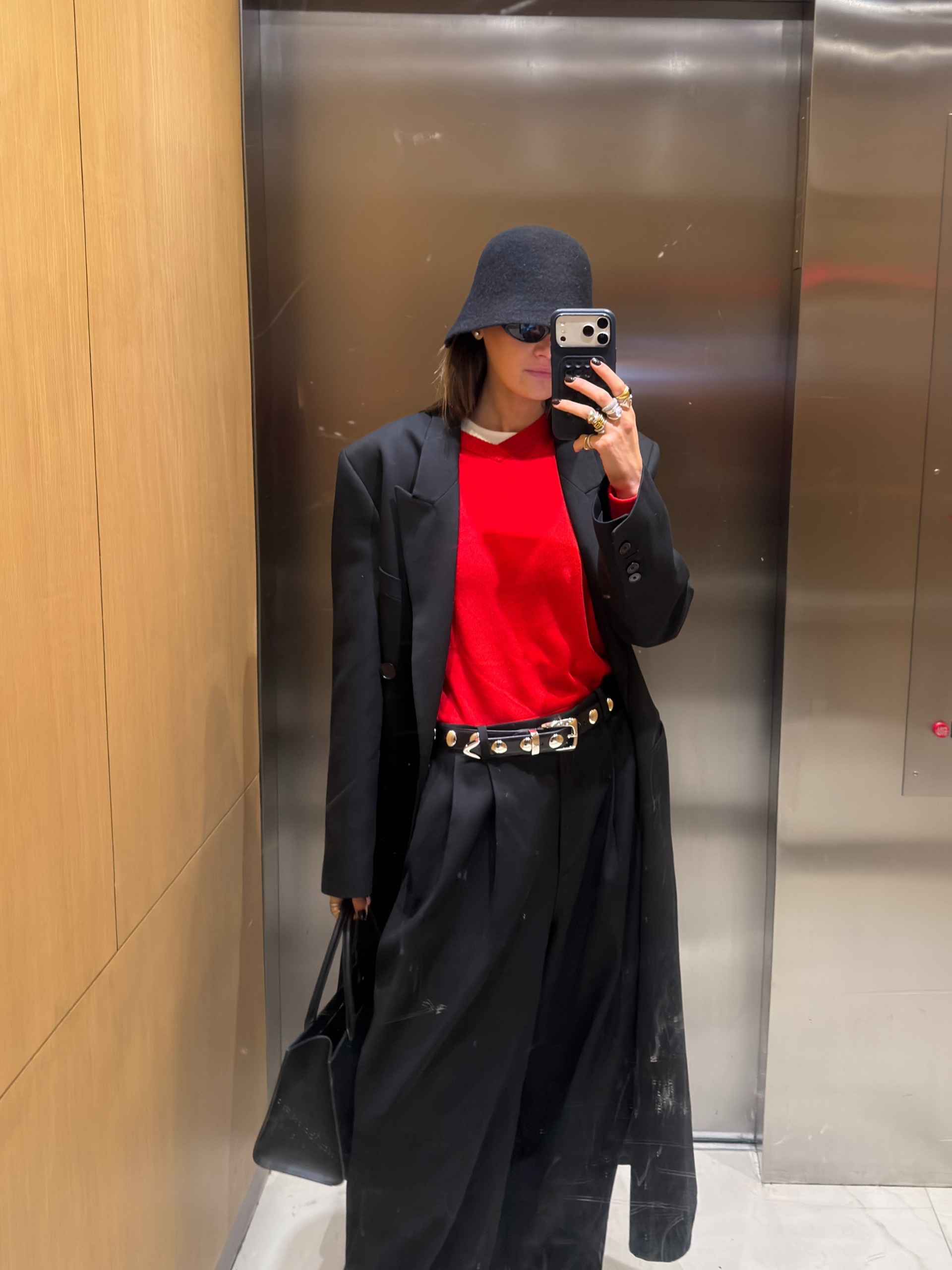 影響者可可希弗 (Coco Schiffer) 穿著紅色毛衣搭配黑色長褲、鑲釘腰帶和黑色外套。