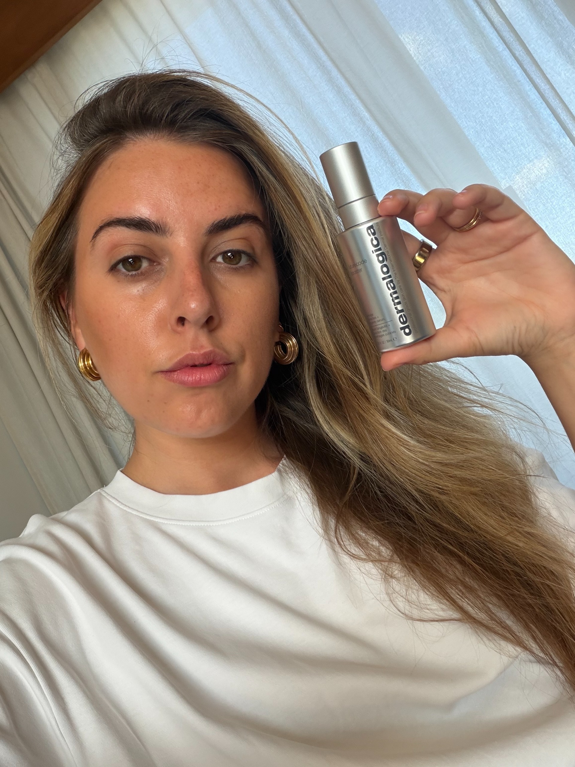 Shannon Lawlor 將一瓶 Dermalogica Futurecode Booster 放在臉旁