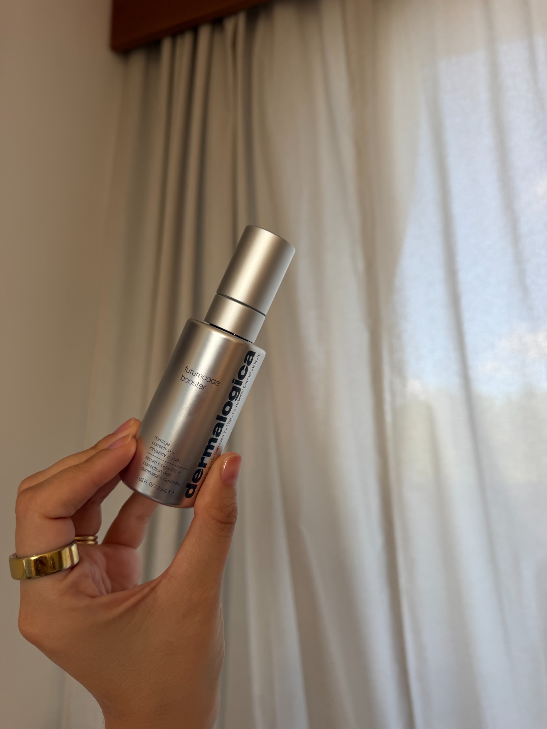 Shannon Lawlor 將一瓶 Dermalogica Futurecode Booster 靠在奶油色窗簾上