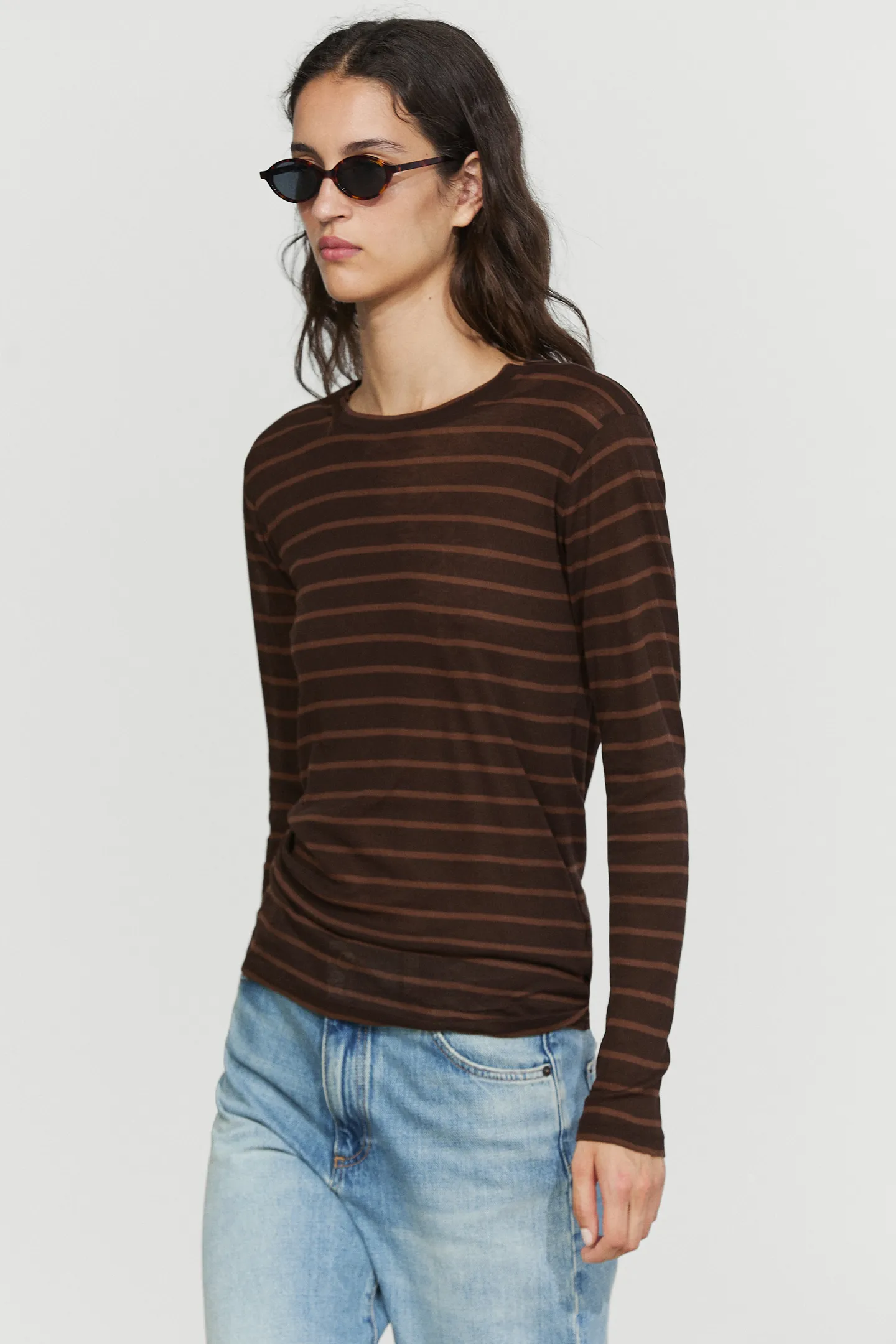 模特兒身穿 Massimo Dutti 棕色條紋長袖 T 卹、牛仔褲和太陽眼鏡。