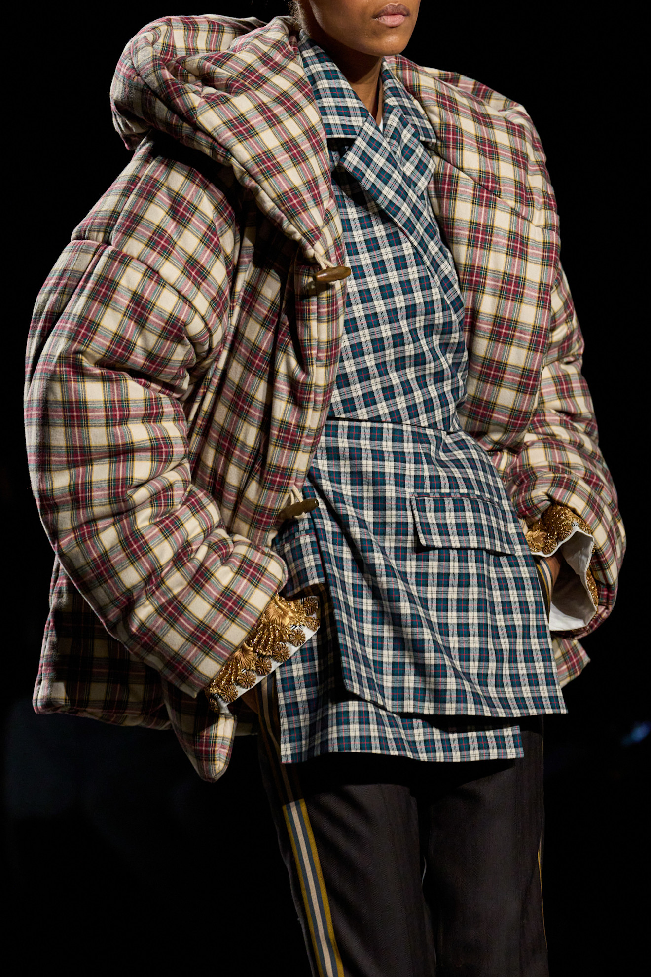 模特兒穿著格紋羽絨外套搭配格紋西裝外套走在 Dries Van Noten 的 27 秋冬秀場上