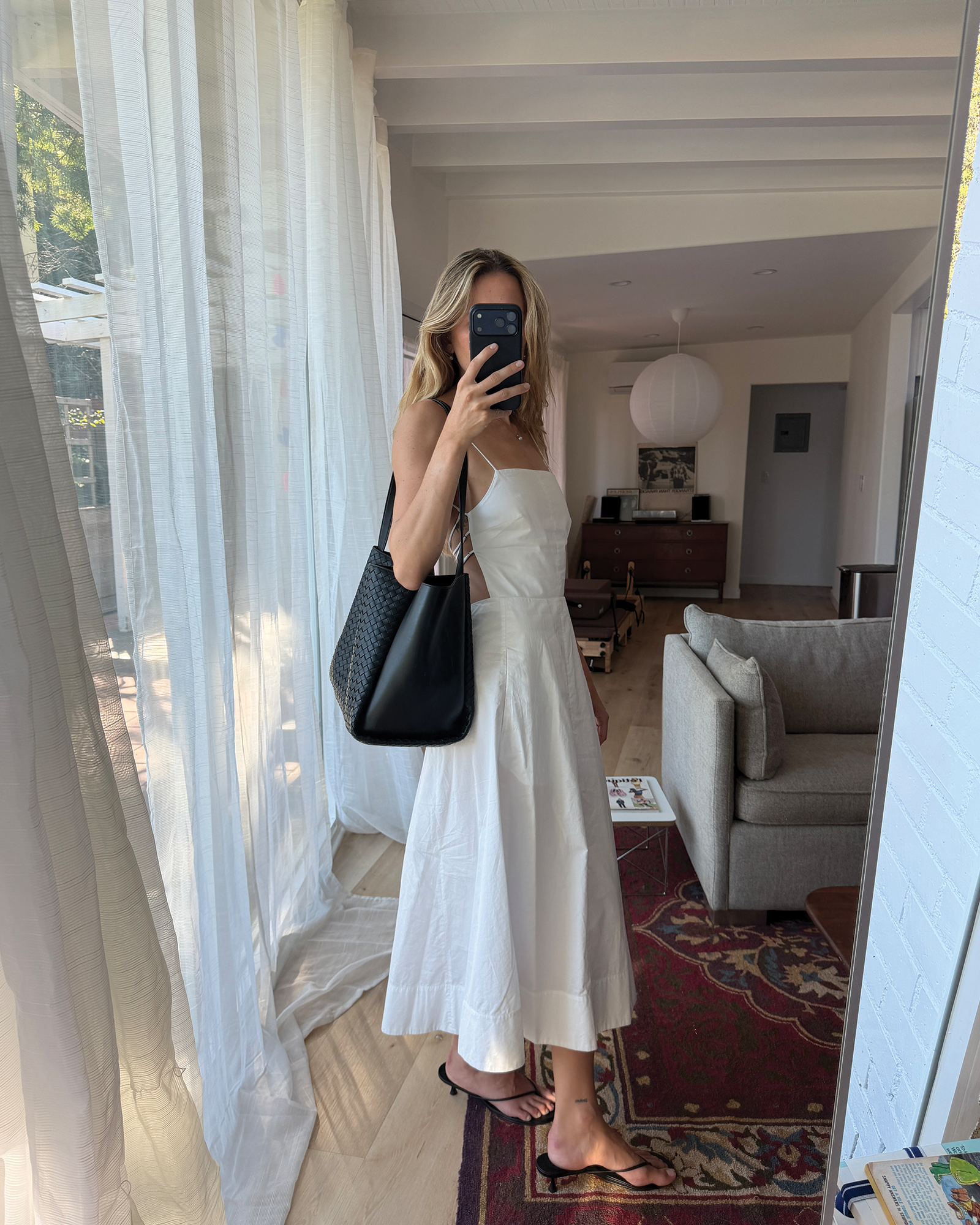 Eliza Huber 穿著白色洋裝、涼鞋和新款 Bottega Veneta Corso 包款。