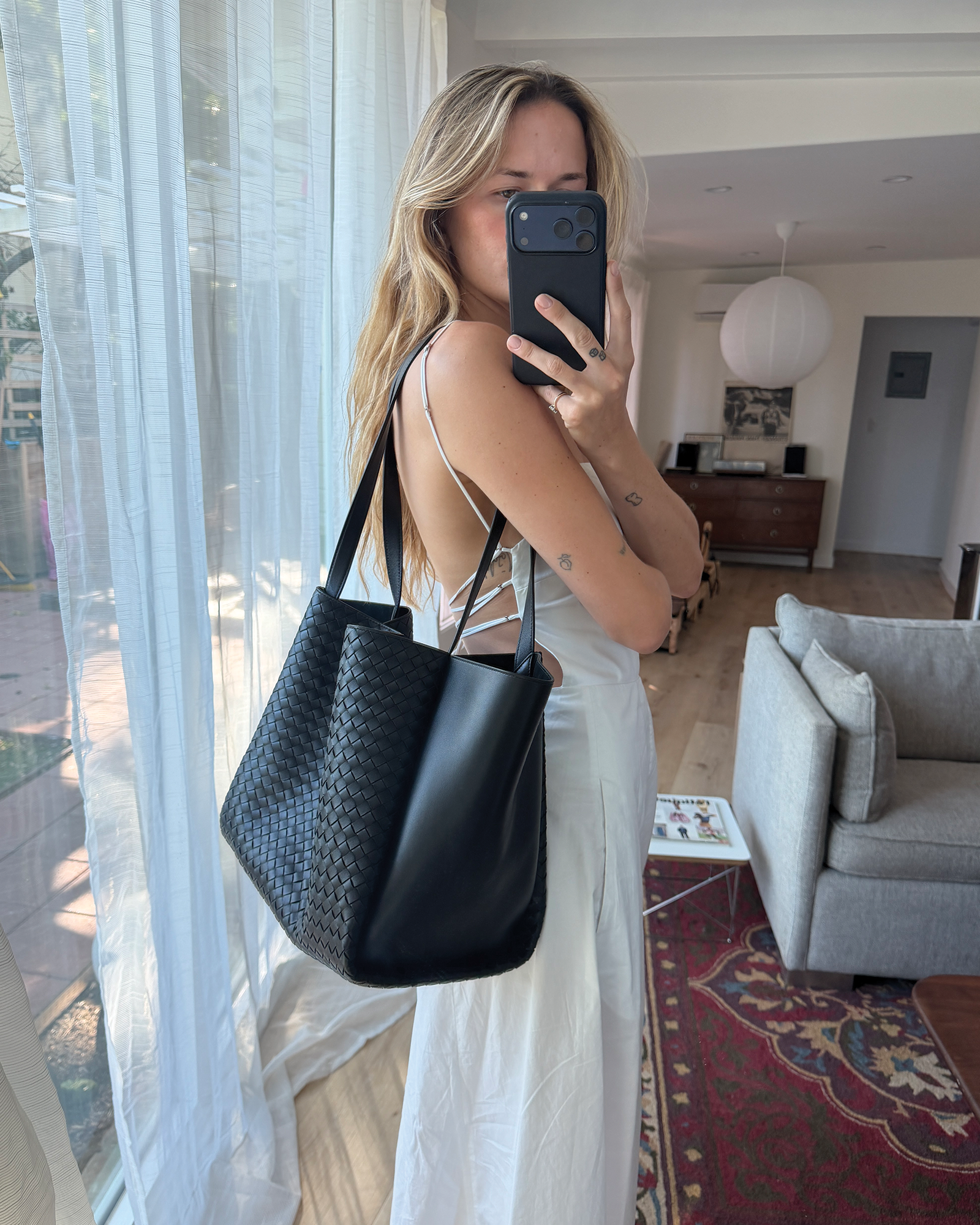 Eliza Huber 穿著白色洋裝、涼鞋和新款 Bottega Veneta Corso 包款。